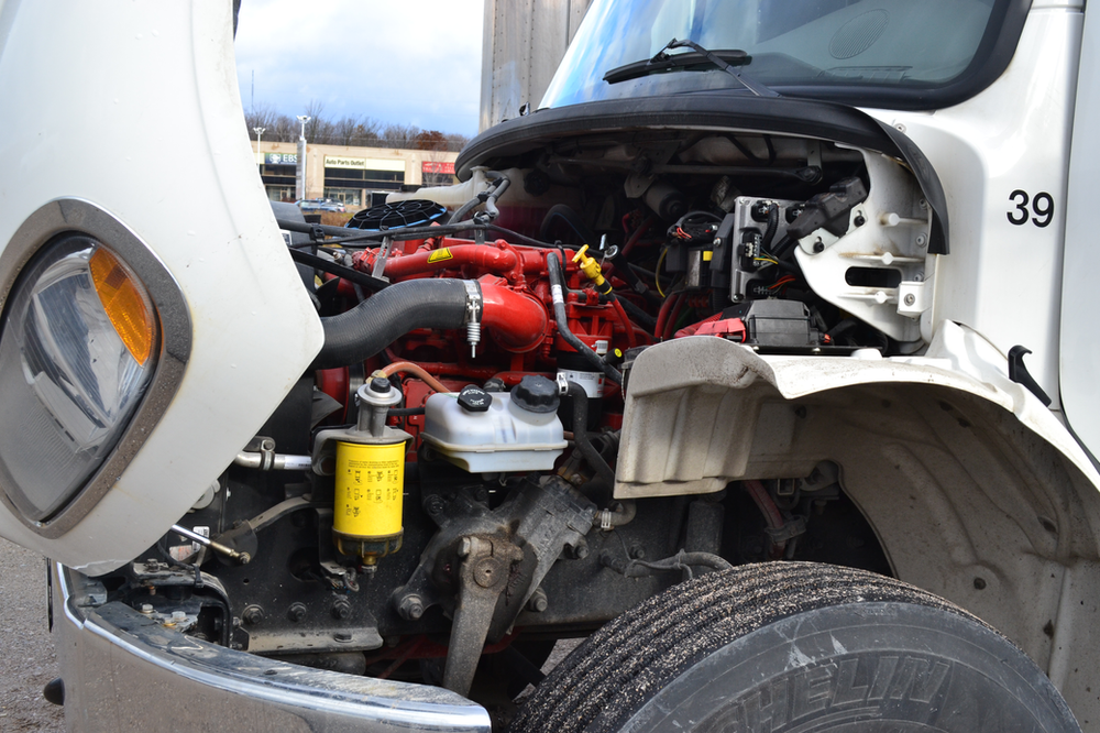 A close-up of a truck with its hood open, revealing the engine and other internal components. The image shows various parts, including hoses, a yellow fluid reservoir, and a tire. The number 39 is visible on the truck's front side.